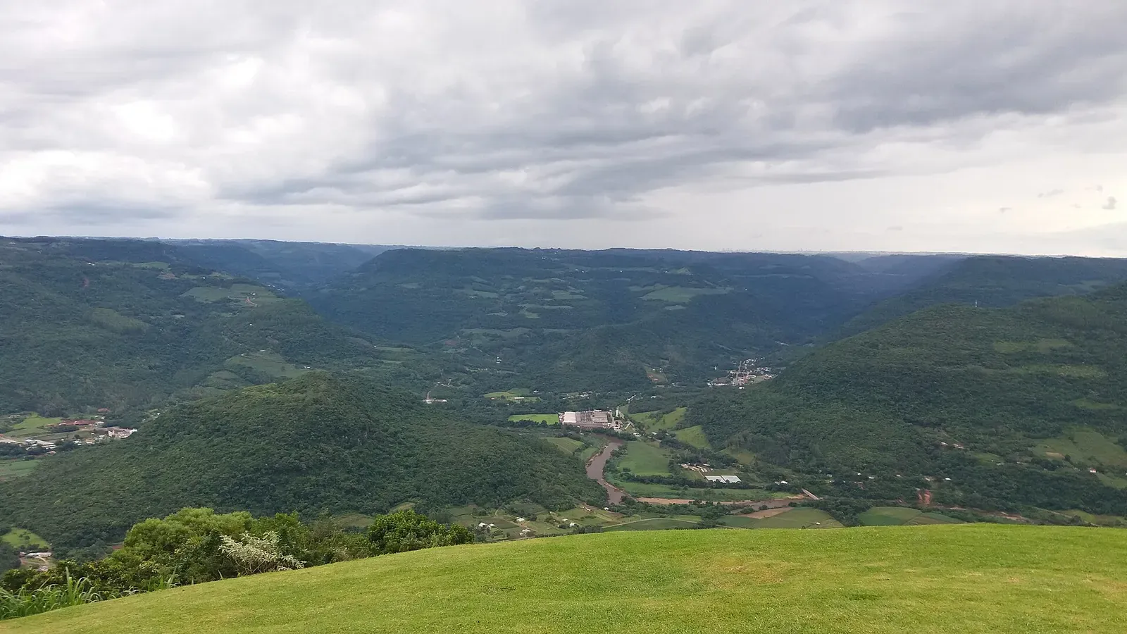 Vale do Caí visto do Ninho das Águias, com morros verdes e o rio no fundo