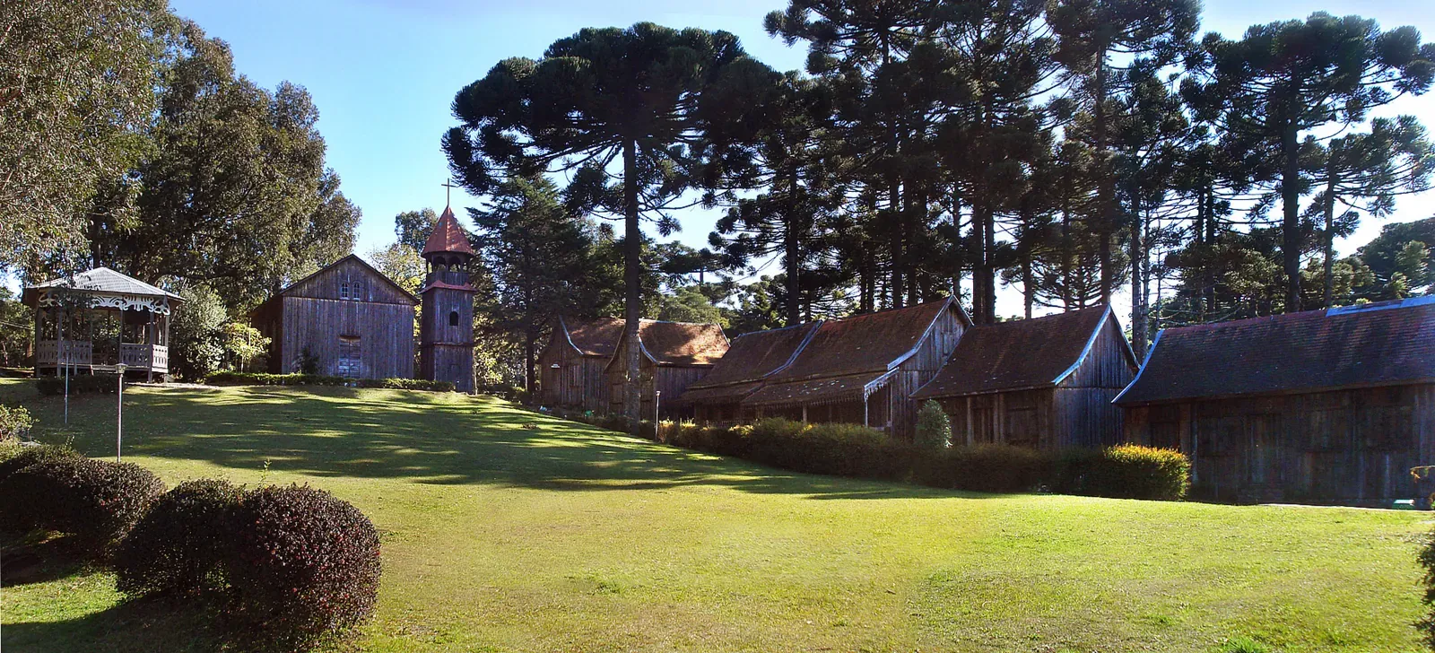 Casas de madeira da Réplica de Caxias de 1885 entre araucárias