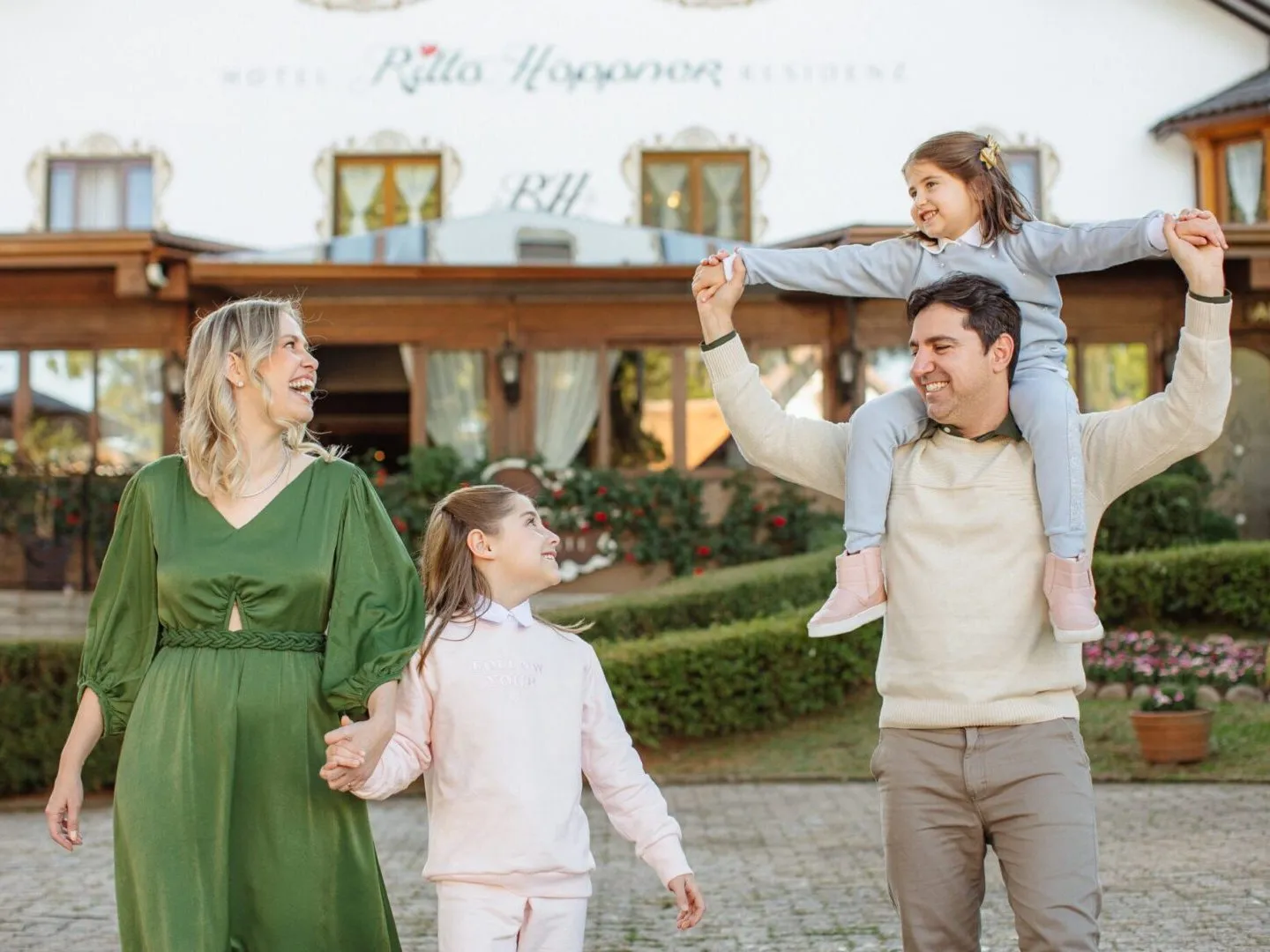 Família caminhando no jardim em frente à fachada do Hotel Ritta Höppner, em Gramado