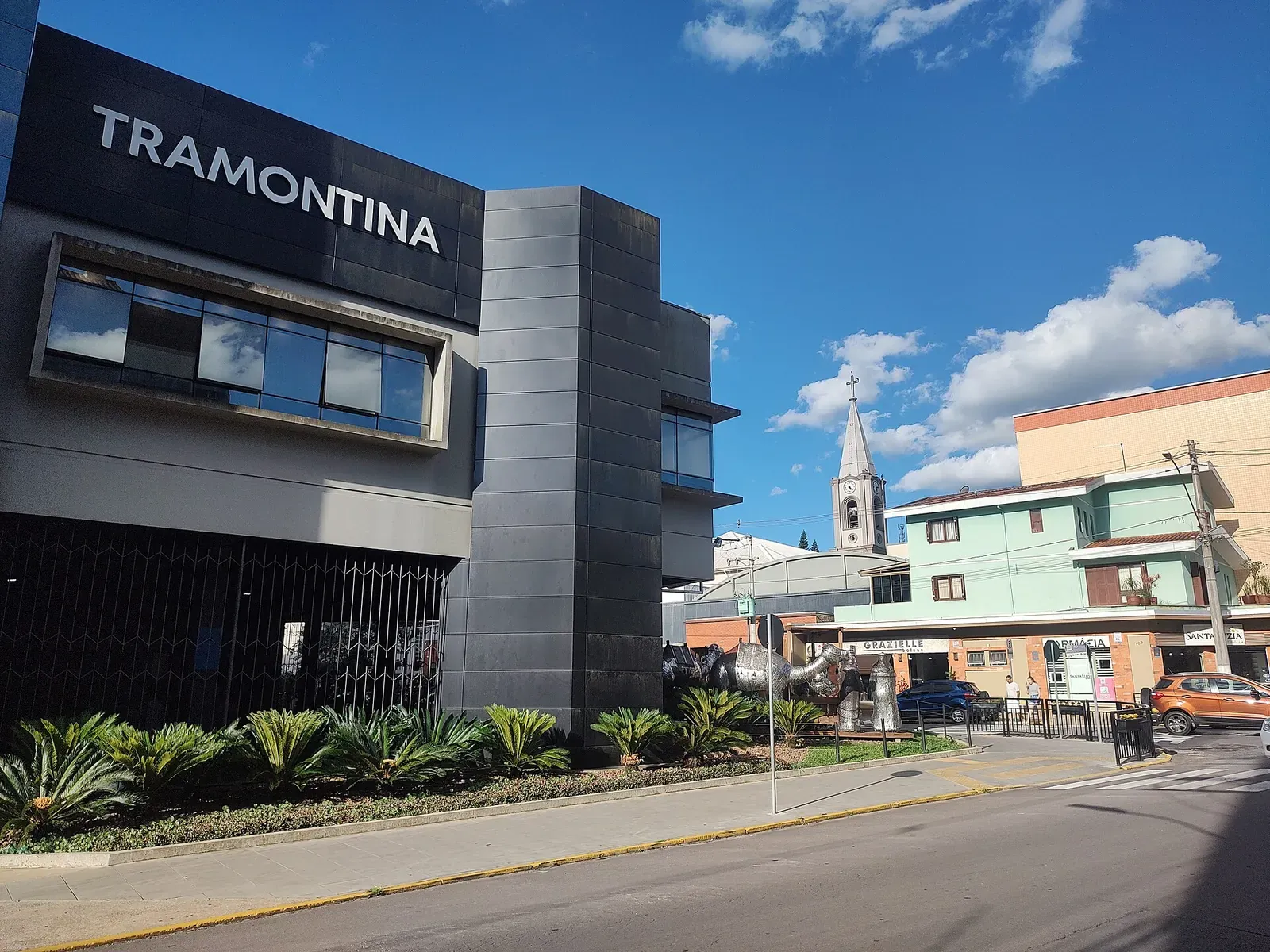 Prédio da Tramontina no centro de Carlos Barbosa, com a torre da igreja ao fundo